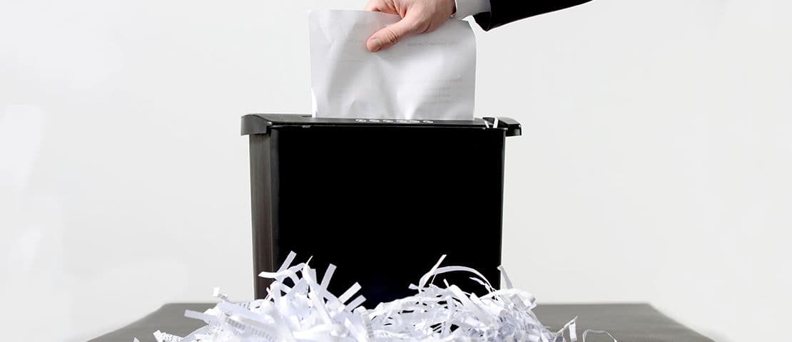 Aktenvernichter mit geschredderten Papierstreifen zur DSGVO-konformen Dokumentenvernichtung