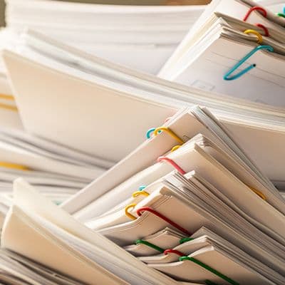 Stapel von Dokumenten und Aktenordnern die datenschutzkonform vernichtet werden müssen