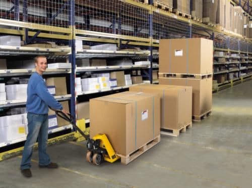 Mitarbeiter transportiert Palette mit Handhubwagen im Lager